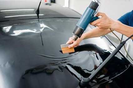 Professional window tint installer applying tint to a car window, ensuring a smooth finish.